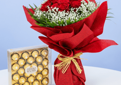 A bouquet of red roses and white baby's breath next to a box of Ferrero Rocher chocolates
