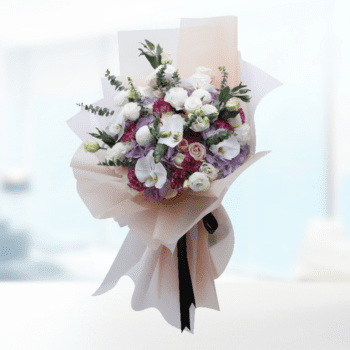 A luxurious bouquet featuring vibrant roses, lilies, and greenery, elegantly arranged in a decorative vase.