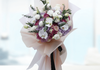 A luxurious bouquet featuring vibrant roses, lilies, and greenery, elegantly arranged in a decorative vase.