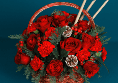 A basket filled with roses, carnations, and hypericum berries, adorned with luxury Christmas foliage and various decorative elements.
