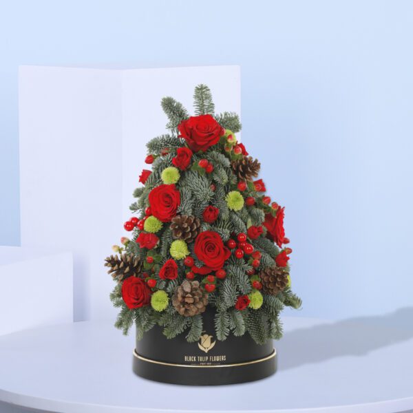 A Christmas tree-shaped floral arrangement in a black pot. The arrangement features red roses, green foliage, pine cones, and berries.