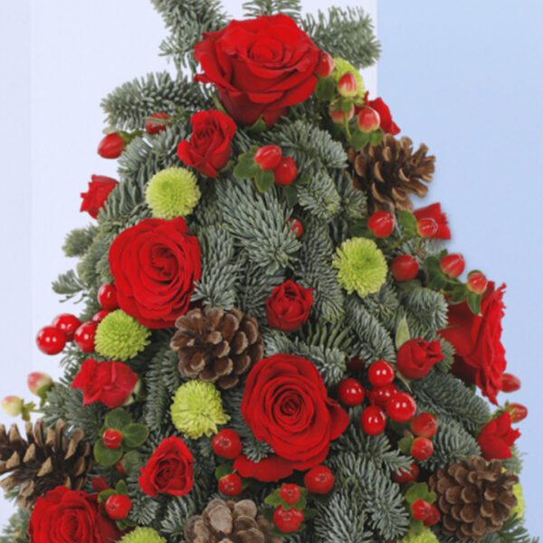 A Christmas tree-shaped floral arrangement in a black pot. The arrangement features red roses, green foliage, pine cones, and berries.