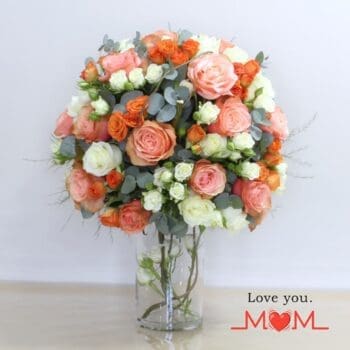 A vibrant arrangement of orange, peach, and white roses in a cylinder vase, ideal for conveying friendship and affection.