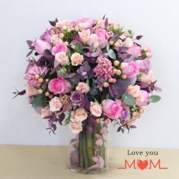 Elegant round vase containing pink and peach roses, representing hope and positivity through their vibrant colors.