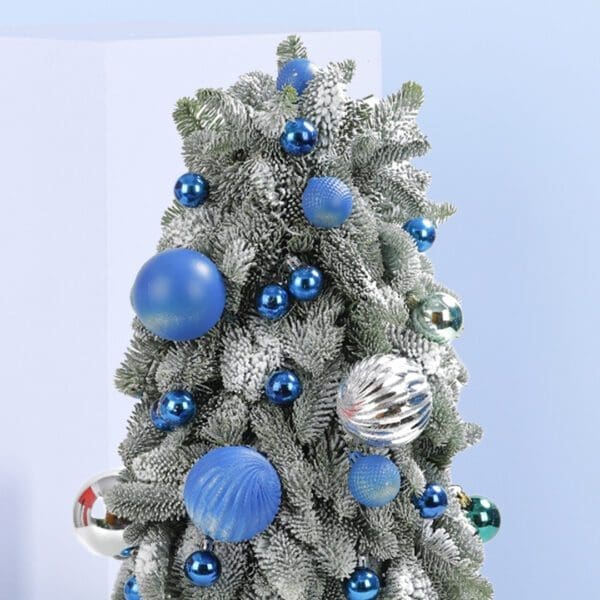 4 (58) A small, frosted Christmas tree decorated with blue and silver ornaments. The tree is in a white pot and sits on a blue background.