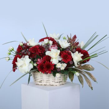 Basket arrangement of red chrysanthemums and white roses with lush greenery for a stunning floral display.