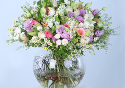 Pink gerberas, pink roses, white ohara lilies, tanacetum, bublurium, white lilies, mathiola, purple lisianthus, and white baby roses in a glass vase.