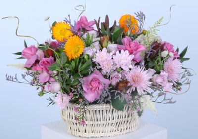 A decorative basket overflowing with colourful flowers is displayed on a pedestal, highlighting its natural beauty and charm.