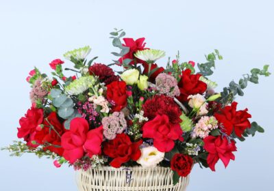 A flower Basket of mixed shades of flowers, featuring roses, carnations, lisianthus, wax flowers, and eucalyptus