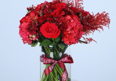 A clear glass vase filled with vibrant red flowers, adding a pop of colour to any event.