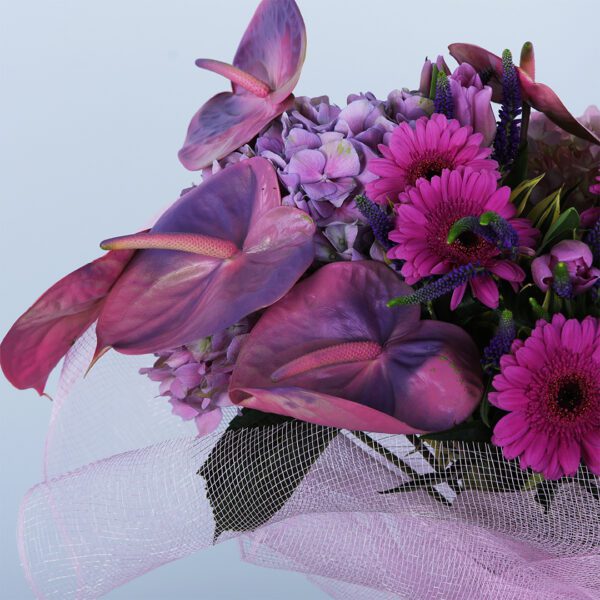 A colourful and exciting pink flower bouquet wrapped in a net.