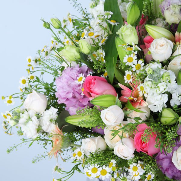 A stunning bouquet of pink and white flowers, including gerberas, roses, lilies, and other varieties, displayed in a glass vase.