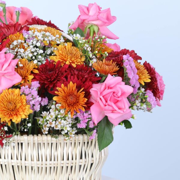 An elegant display of a basket filled with colourful flowers on a white pedestal.