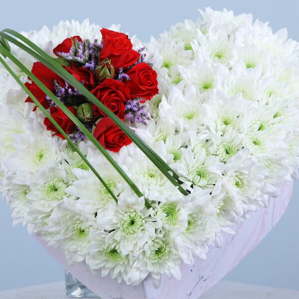 This heart-shaped arrangement features vibrant red and white blooms, making a stunning centerpiece for any celebration.