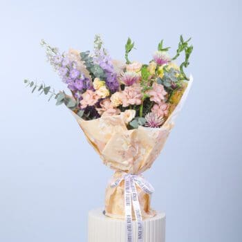 A beautiful bouquet featuring peach roses, delphinium, and lush greenery in an elegant arrangement.
