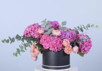 Stylish flower box featuring dark pink hydrangeas, peach roses, and eucalyptus leaves.