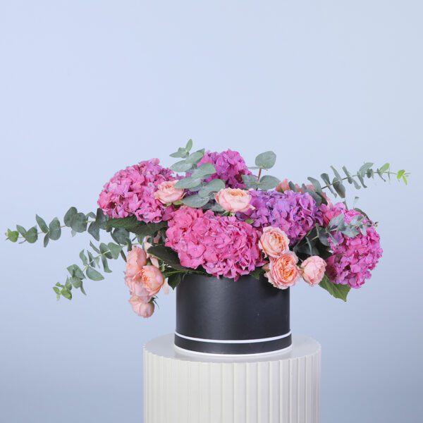 Stylish flower box featuring dark pink hydrangeas, peach roses, and eucalyptus leaves.