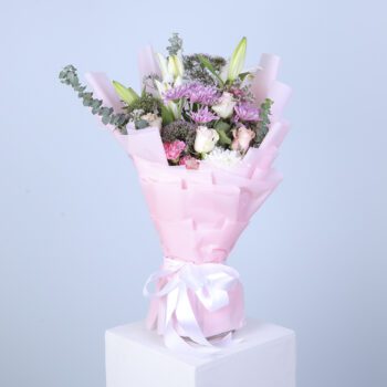 Elegant mixed flowers artfully arranged in a soft pink floral wrap, showcasing their beauty and charm.