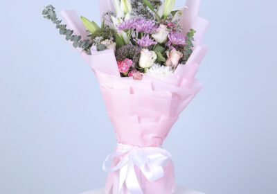 Elegant mixed flowers artfully arranged in a soft pink floral wrap, showcasing their beauty and charm.