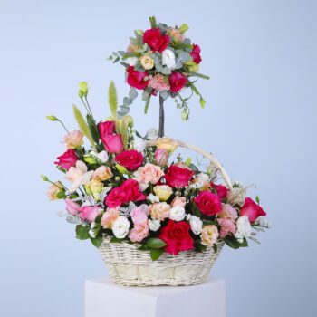 A colorful basket of various shades of roses, featuring a small rose tree and cascading blooms.