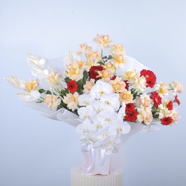 A vibrant bouquet with peach roses, white anthurium, phalaenopsis orchids, red gerberas, and greenery.