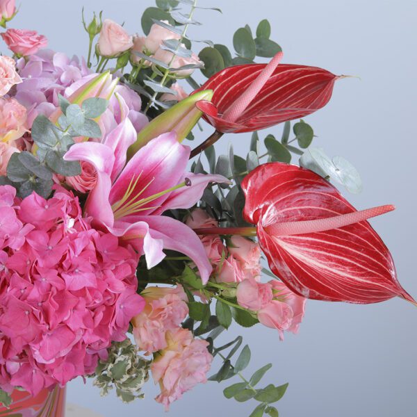 Colorful Floral Arrangement with 3 Pink Hydrangeas, 3 Dark Pink Hydrangeas, 5 Red Anthurium, 5 Baby Roses, 5 Lisianthus, 2 Lilies, and Greenery in a Vase