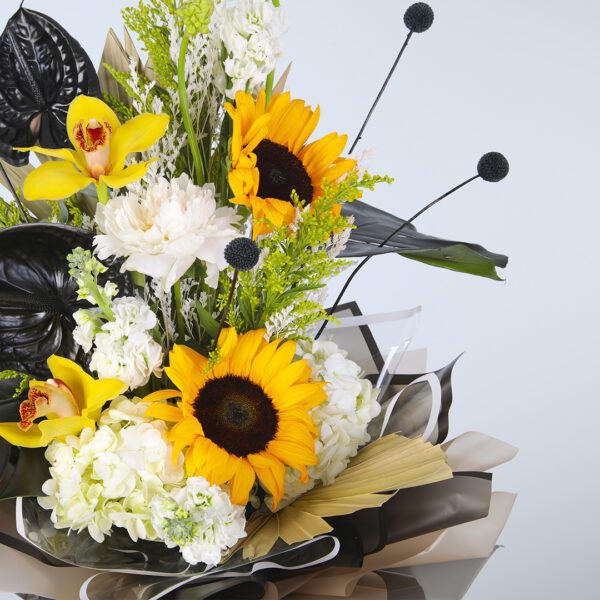 Bright sunflowers paired with striking black foliage, artfully presented on a pedestal.