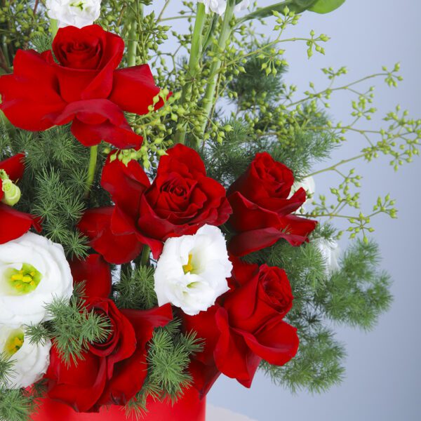 A thoughtfully curated floral hat box, filled with red roses, Mathiolla, and lisianthus, complemented by lush greens.