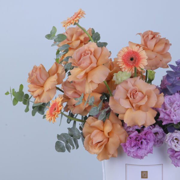 Vibrant floral arrangement featuring roses, gerberas, lisianthus, and greens in a box.