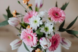 A colorful bouquet of pink and white gerberas, white chrysanthemums, and tulips, arranged in a vase.