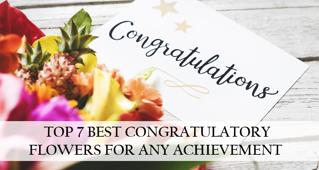 A colorful bouquet of flowers is placed on a wooden table, with a white card reading "Congratulations" lying on top. The text "TOP 7 BEST CONGRATULATORY FLOWERS FOR ANY ACHIEVEMENT" is superimposed over the image.