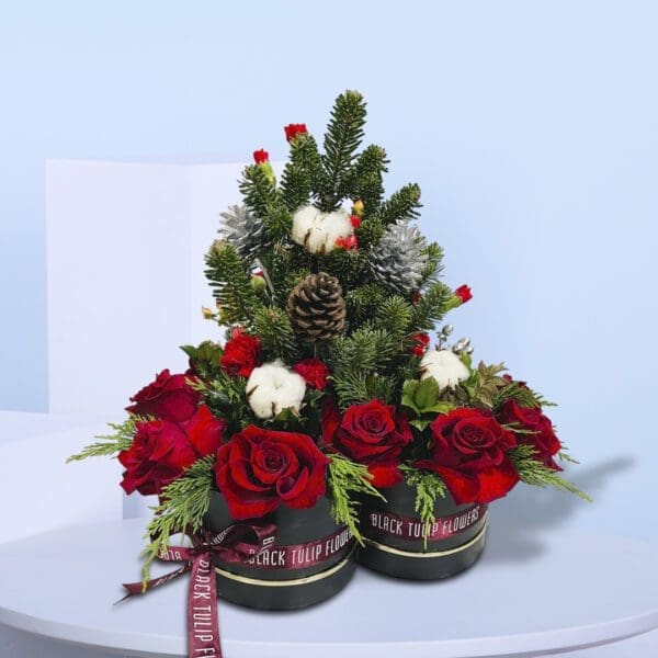 1 (260) Two black gift boxes of Christmas floral arrangement with red roses, evergreen branches, pinecones, and cotton stems .