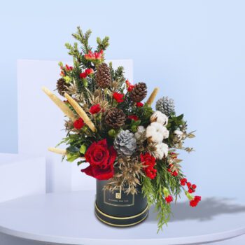 Christmas flower box with red roses, white cotton, pinecones, and festive greens for elegant holiday decoration