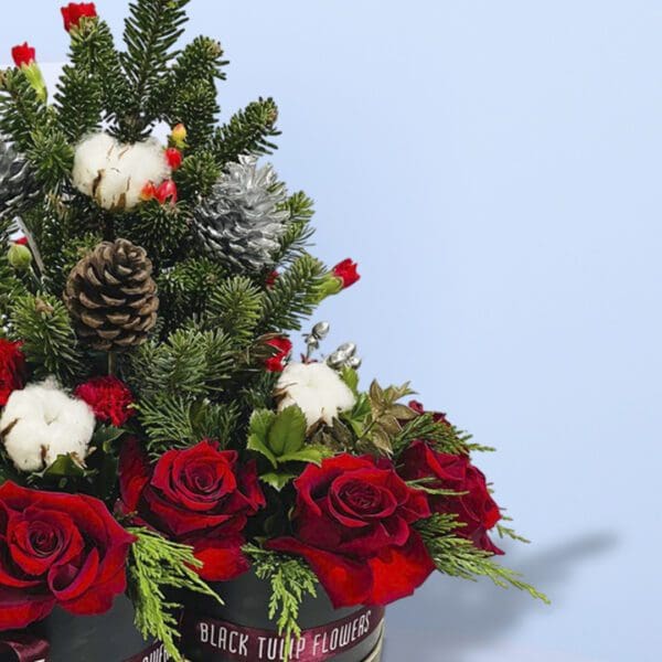 2 (258) Two black gift boxes of Christmas floral arrangement with red roses, evergreen branches, pinecones, and cotton stems .