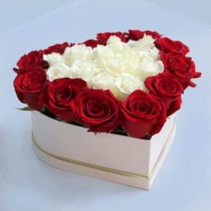 The image shows a heart-shaped box filled with red and white roses. The roses are arranged in a way that creates a beautiful pattern, with the red roses forming the outer border of the heart and the white roses filling the center.