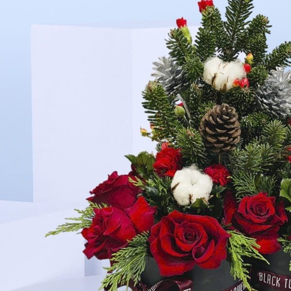3 (93) Two black gift boxes of Christmas floral arrangement with red roses, evergreen branches, pinecones, and cotton stems .
