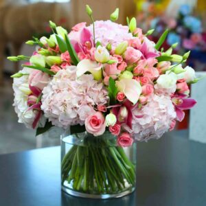 The image shows a stunning flower arrangement in a clear glass vase. The arrangement features a variety of beautiful flowers