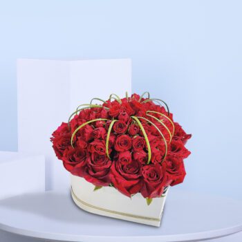 A heart-shaped arrangement of red roses with green accents for Valentine's Day.