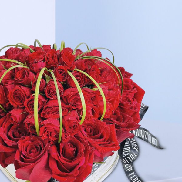 A heart-shaped arrangement of red roses with green accents for Valentine's Day.