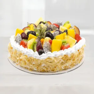 The image shows a delicious-looking fruit cake. It is decorated with a variety of colorful fruits, including pineapple, kiwi, grapes, and dragon fruit. The cake is also topped with whipped cream and almond flakes. It looks like a perfect treat for a special occasion or a refreshing summer dessert.