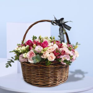 A mix of pink, white, and red flowers are arranged inside the basket.