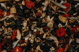 Close-up of a mixture of dried herbs, berries, and possibly flowers, with dominant colors of red, brown, and beige.