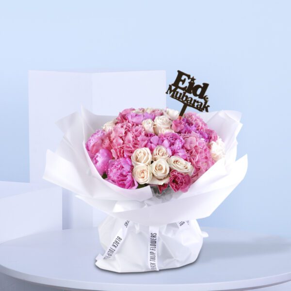 Pink and white floral bouquet wrapped in white with an "Eid Mubarak" topper.