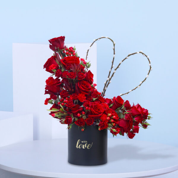 A black vase filled with vibrant red roses, adorned with a heart-shaped tag for a romantic touch.