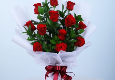 A bouquet of red roses hand-wrapped in a white sheet, placed on a presentable table.