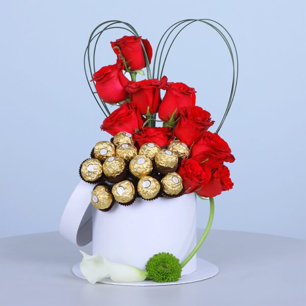 A white basket with red roses, Ferrero Rocher chocolates, and decorative heart-shaped loops, perfect for gifting.