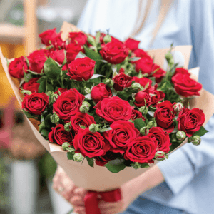 A bouquet of red roses wrapped in brown paper.