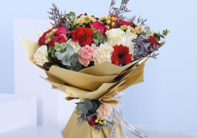 Bouquet with red, white, and pink roses, carnations, and gerberas, wrapped in stylish kraft paper.