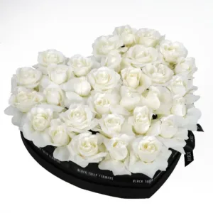 Heart-shaped arrangement of white roses in a black box.
