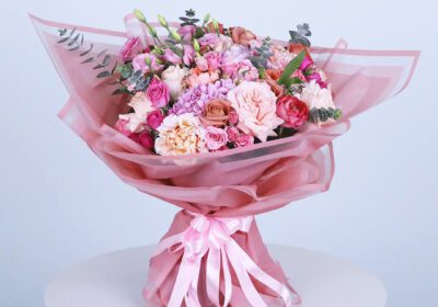 Beautiful hand-tied pink bouquet featuring roses, carnations, and fresh greens.